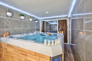 Un espace spa moderne avec un jacuzzi, des bougies et des plantes en pot.