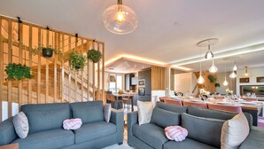 A modern living room with grey sofas, a marble bench, and a wooden wall with plants. - MickeyRelax Luxury Spa Villa near Disneyland Paris (Villeneuve-Le-Comte)