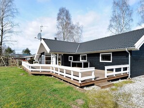 A modern house with a deck, a satellite dish, and a large window.