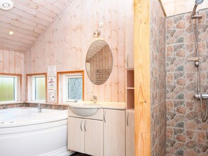 A bathroom with wooden walls, a stone shower, a sink, and a bathtub.