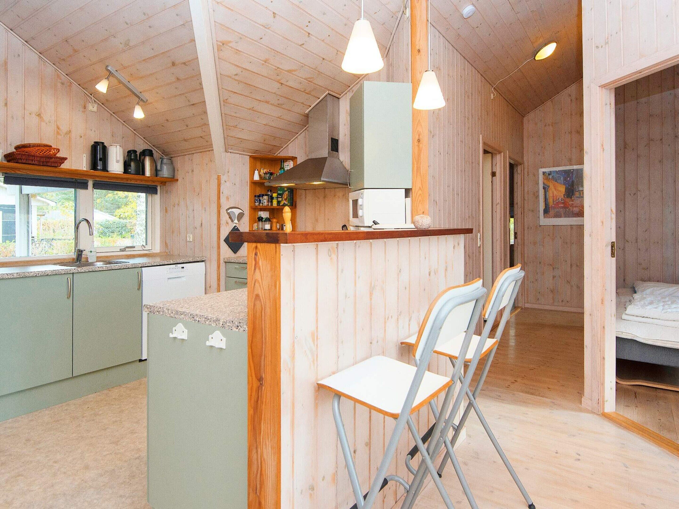 A compact kitchen with a bar area, a dining space with chairs, and a bedroom with a bed.