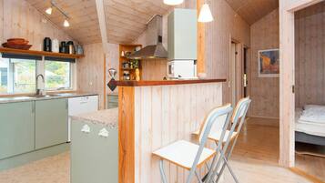 A compact kitchen with a bar area, a dining space with chairs, and a bedroom with a bed.