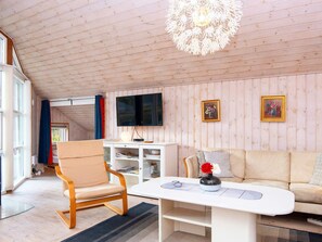 A cozy living room with a wooden ceiling, a flat-screen TV, a sofa, a coffee table, and a chair. - 5 Star Holiday Home in Farvang (Farvang)