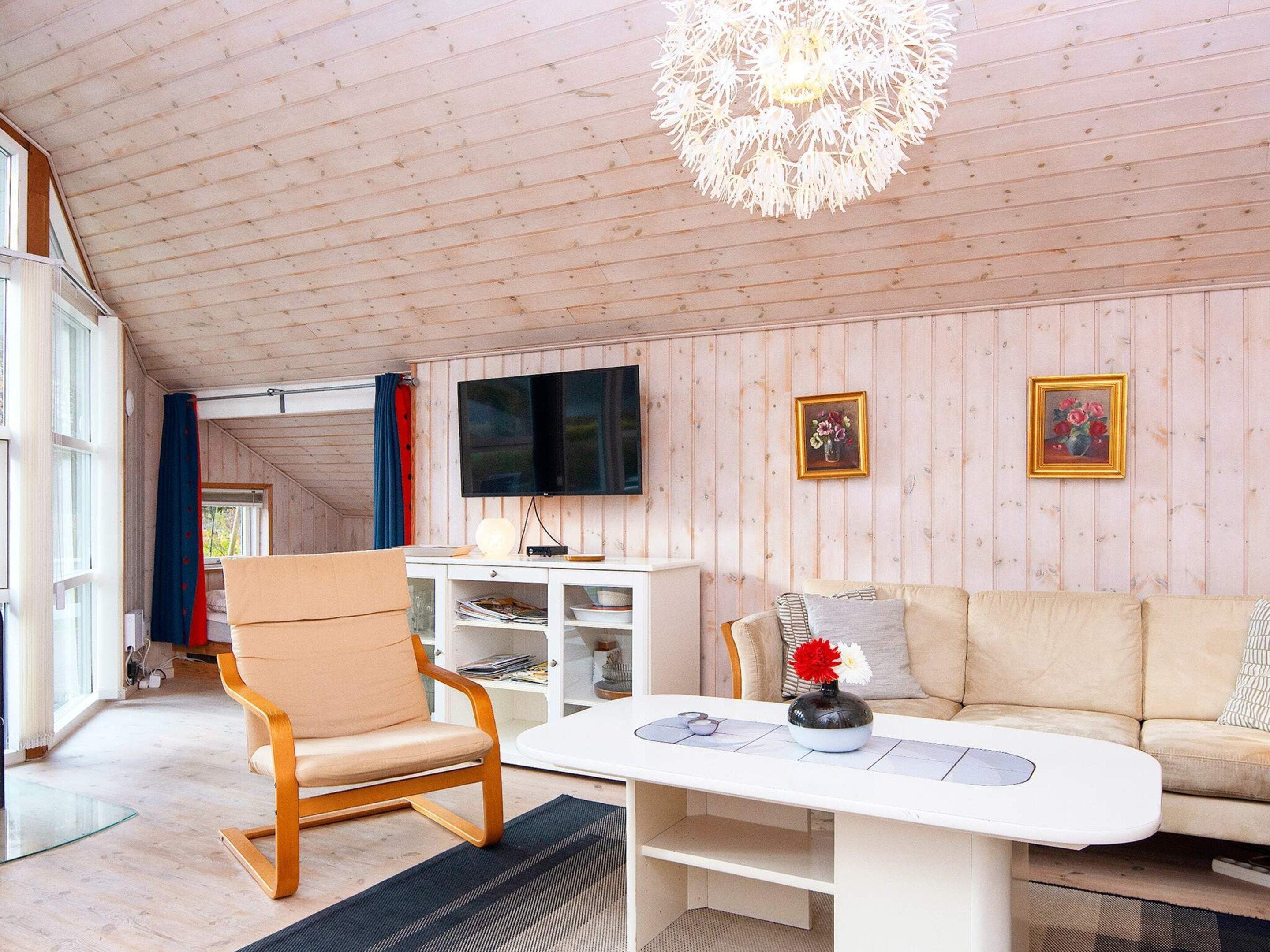 Ein modernes Wohnzimmer mit Holzboden, einem Flachbildfernseher, einem Sofa, einem Couchtisch und einem Sessel.