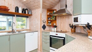 A kitchen with wooden cabinets, a dishwasher, an oven, and a microwave. - 5 Star Holiday Home in Farvang (Farvang)