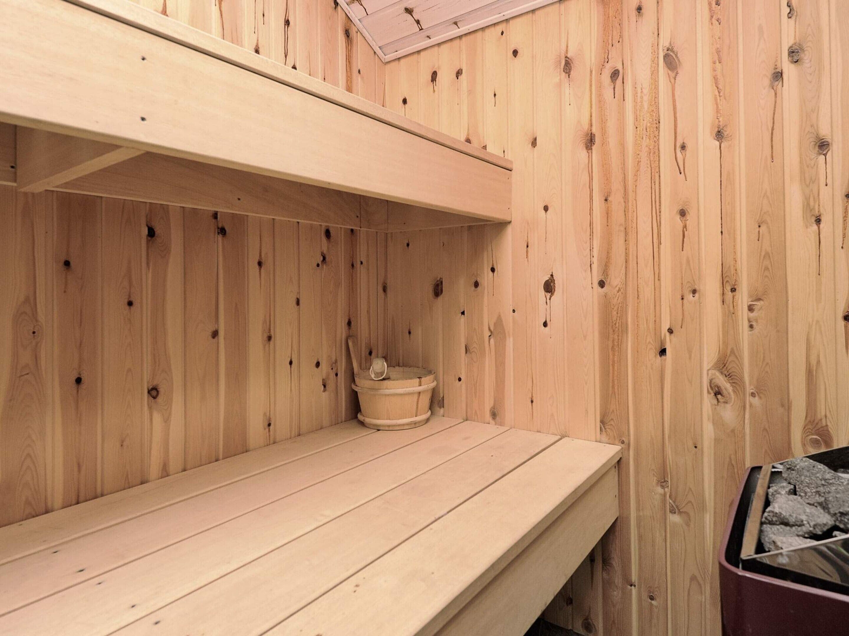 Una sauna in legno con una panca e un piccolo recipiente di legno.