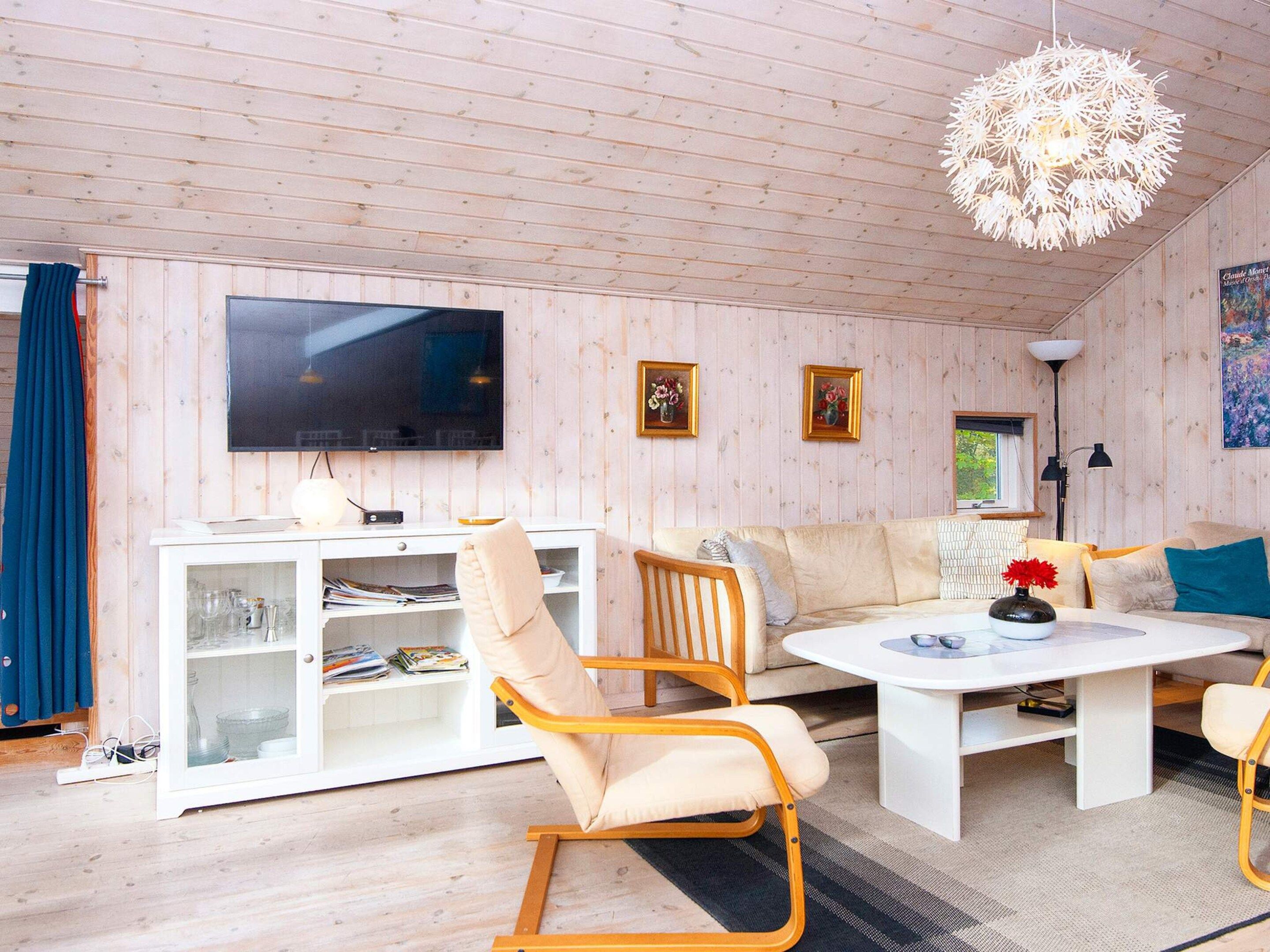 A modern living room with a television, sofa, coffee table, and a decorative chandelier.