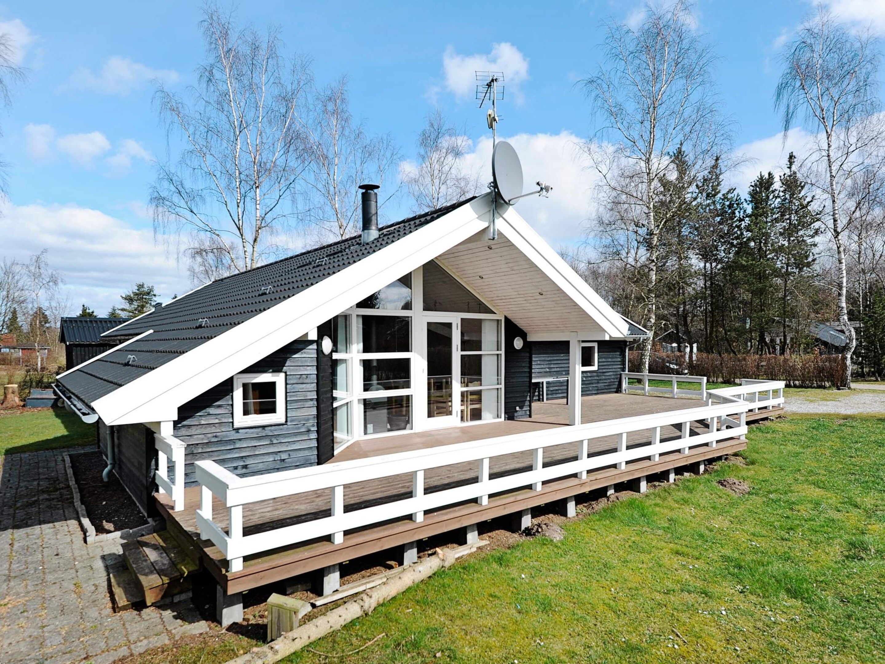 Una casa moderna con tetto spiovente, ampie finestre e un patio in legno.