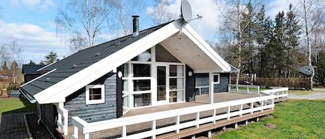 Una casa moderna con tetto spiovente, ampie finestre e un patio in legno.