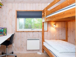 A bunk bed room with a desk and chair, a window with a view of trees, and a wall-mounted heater. - 5 Star Holiday Home in Farvang (Farvang)