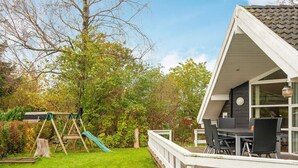 A residential property with a deck, a swing set, and a dining area with outdoor furniture. - 5 Star Holiday Home in Farvang (Farvang)