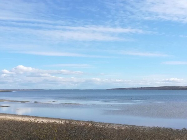 Un paisaje costero con cielo despejado, mar tranquilo y tierra a lo lejos.