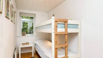 A bunk bed room with a small table and a window.