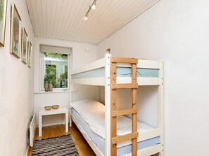 Dormitorio con literas, una mesita y una ventana.