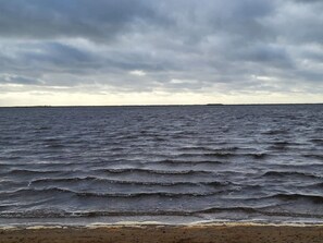 En strand med bølger og en overskyet himmel.