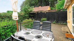 Een terras met een tafel en stoelen, een overdekte parasol en een houten hek op de achtergrond.
