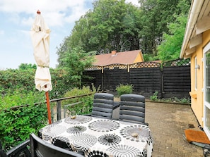Eine Terrasse mit Tisch und Stühlen, einem Sonnenschirm und einem Holzzaun im Hintergrund.
