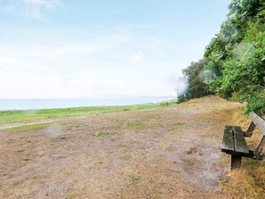 Banco perto de uma área gramada, com vista para o mar.
