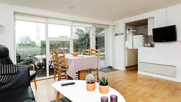 Uma sala de estar moderna com área de jantar, cozinha e televisão.