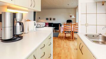 A compact kitchen with modern appliances, a dining area with a table and chairs, and a visible sink.