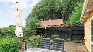Une terrasse avec une table et des chaises, une clôture en bois et une maison en arrière-plan.