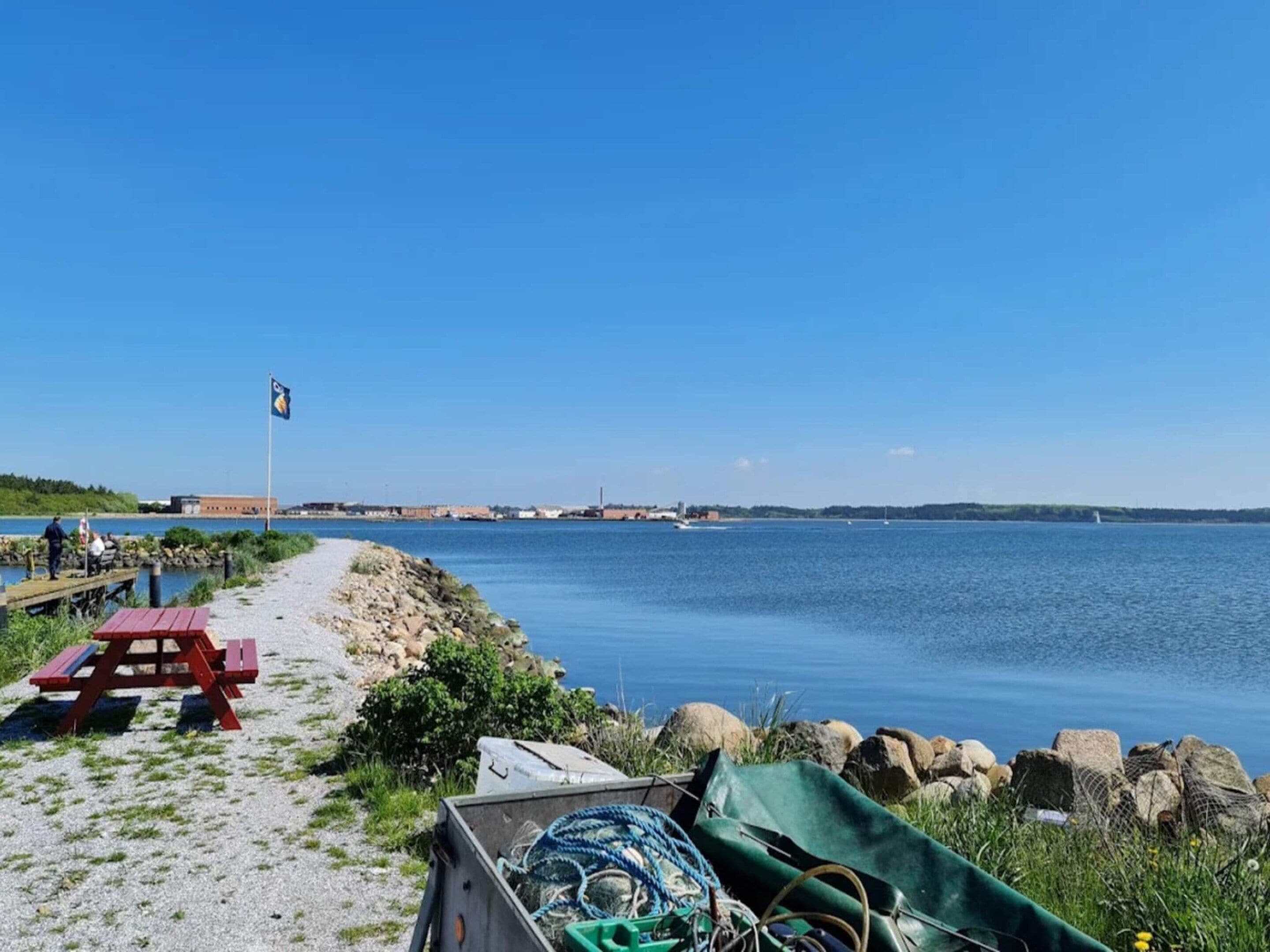 A coastal area with a picnic table, a flag, and a rocky shoreline.