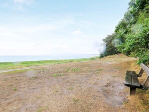 Eine Bank an einer grünen Fläche mit Blick aufs Meer.