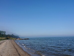 A beach with a clear sky, a rocky shoreline, and a calm sea. - 4 Person Holiday Home in Nykobing M (Nykobing Mors)