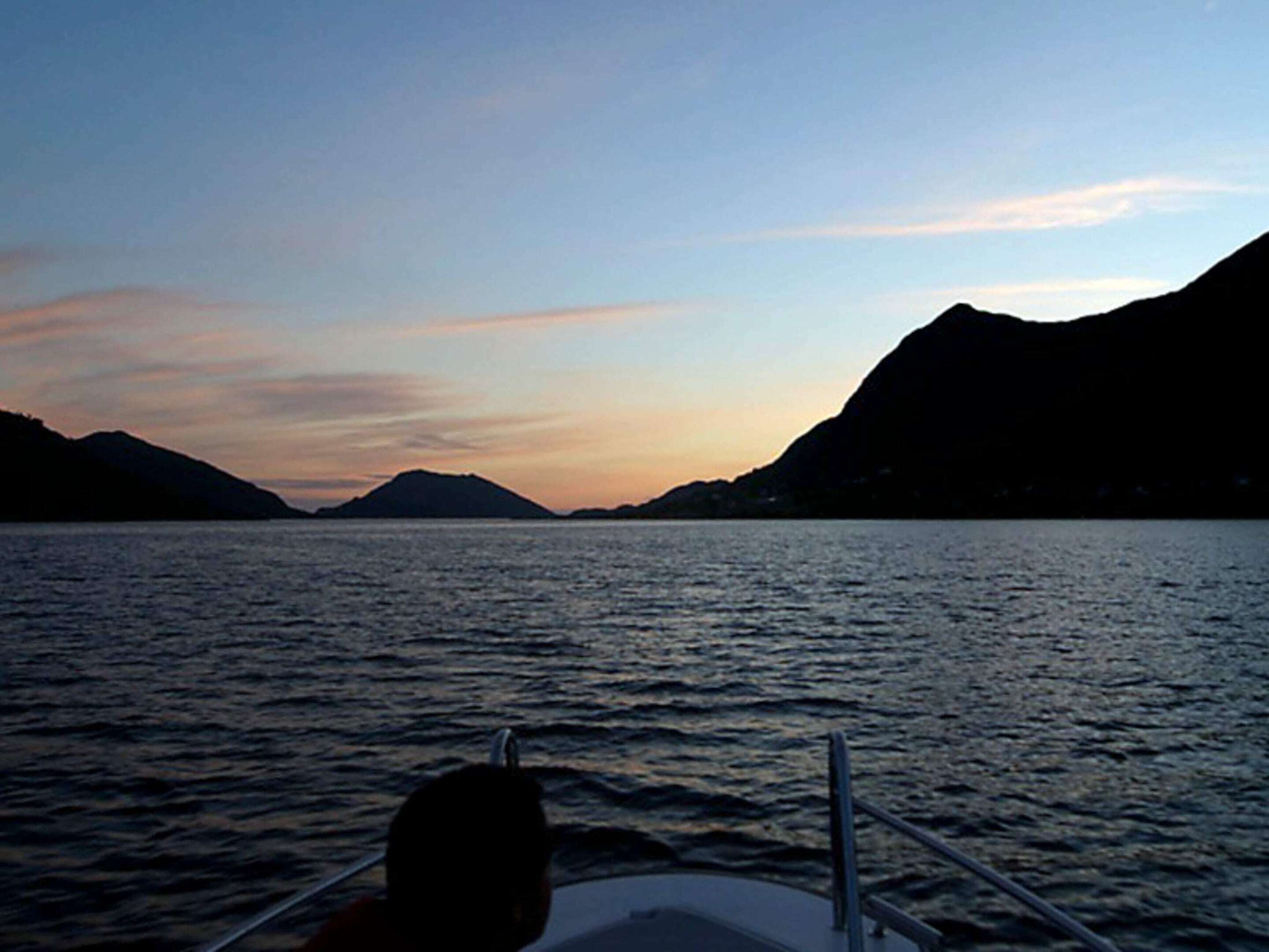 Una barca su acqua calma con montagne sullo sfondo.