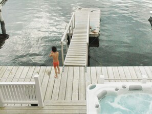 A wooden dock leading to a body of water, a hot tub, and a white fence. - Holiday Home in Gursken (Sande)