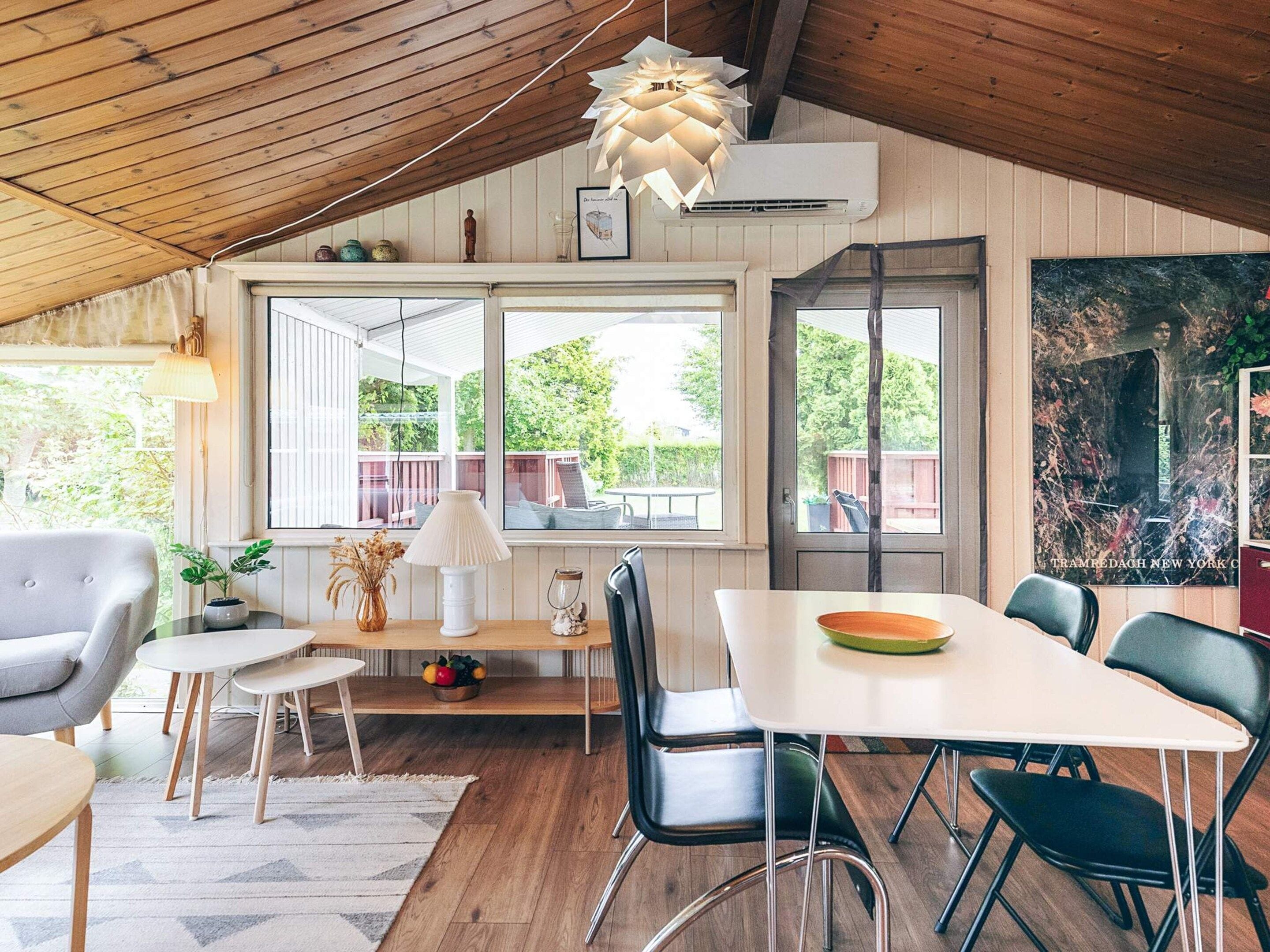 Uma sala de jantar com mesa de madeira, cadeiras e luminária pendente.