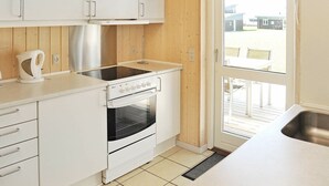 A compact kitchen with white cabinets, a built-in oven, a kettle, and a window to the outside. - Modern Holiday Home in Faaborg With Balcony (Faaborg)