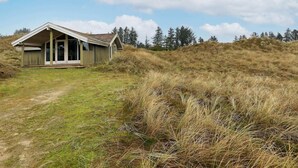 A single-story building with a sloped roof, a front porch, and a door. - 4 Person Holiday Home in Blokhus (Blokhus)