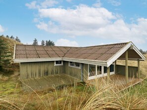A wooden cabin with a sloped roof, a covered porch, and a small window. - 4 Person Holiday Home in Blokhus (Blokhus)