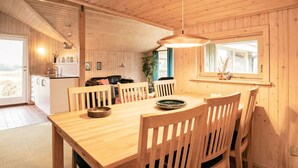 A wooden interior with a dining table, chairs, a hanging light fixture, and a window with a view. - 4 Person Holiday Home in Blokhus (Blokhus)