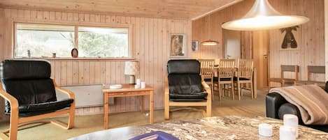 A room with wooden panel walls, a dining table with chairs, a sofa, and a table with a marble top.
