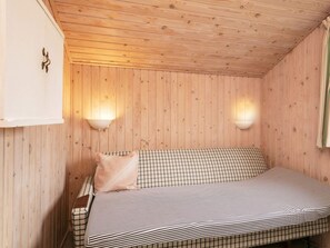 A wooden cabin room with a bed, two wall-mounted lamps, and a white cabinet. - 4 Person Holiday Home in Blokhus (Blokhus)