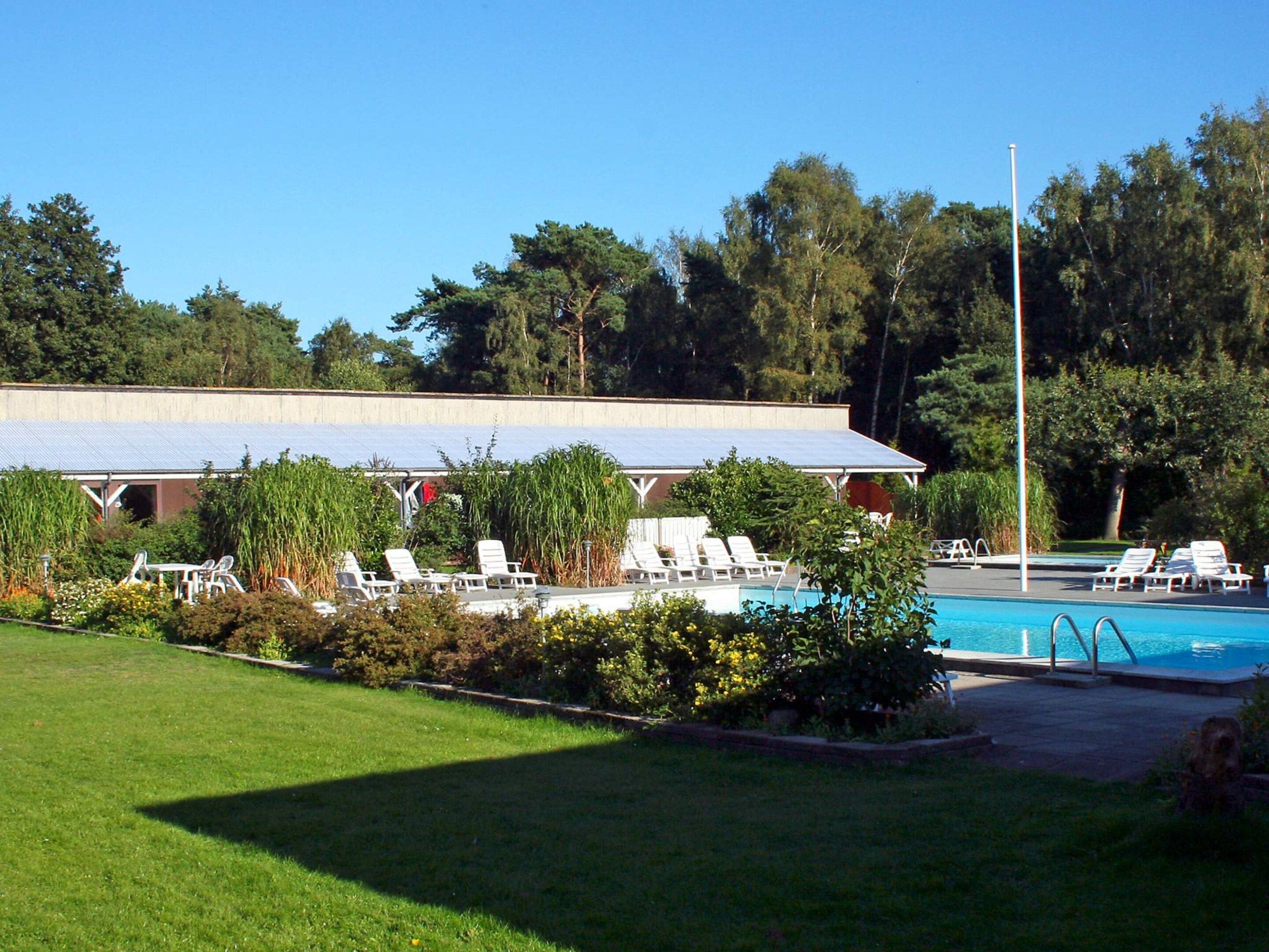 A pool area with lounge chairs and a covered structure.