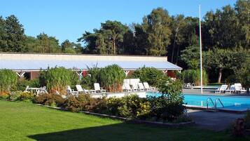 A pool area with lounge chairs and a covered structure.