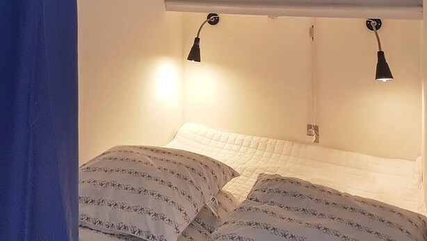 Une chambre à coucher avec un lit, deux lampes de chevet et un tableau encadré au mur.