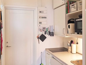 Une cuisine équipée d’un four à micro-ondes, d’un évier et de divers ustensiles.