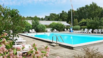 Una piscina con sillas de descanso e izada una bandera.