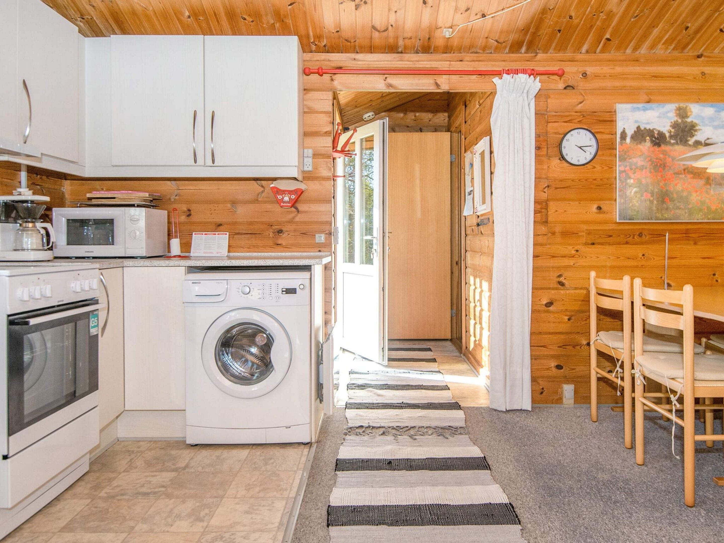 A compact kitchen with a washing machine, microwave, and oven.