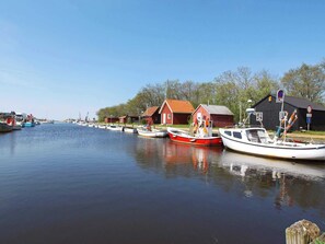 A calm waterway with boats docked, red and white buildings, and trees in the background. - Reposeful Holiday Home in Skjern near Sea (Skjern)