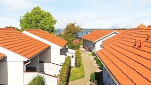 A row of white buildings with orange tiled roofs, arranged in a linear fashion with a pathway between them. - 4 Person Holiday Home in Aeroskobing (Aeroskobing)