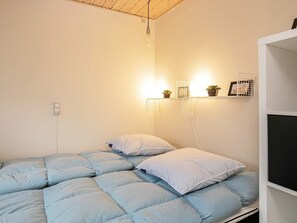 Ein Schlafzimmer mit einem Bett, einer Wandablage mit Pflanzen und einer Steckdose.