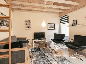 A modern living room with a television, black leather chairs, a wooden ceiling, and a black and white rug. - 4 Person Holiday Home in Aeroskobing (Aeroskobing)