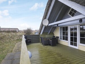 A covered outdoor seating area with a table and chairs, a satellite dish, and a view of the surrounding landscape.