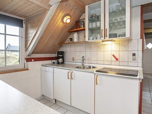 A kitchen with white cabinets, a coffee maker, a sink, and a glass cabinet above the counter.