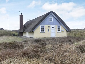 A single-story house with a thatched roof, a chimney, and a small porch.